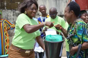 KMJ Foundation volunteer hands a bucket to a woman, June 2023