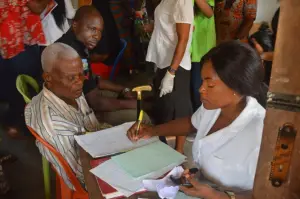 Volunteer registers an elderly patient at the medical outreach
