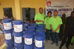 KMJ Foundation team with buckets in front of the Medical Outreach banner